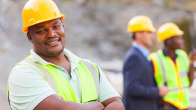 Smiling mine worker at mining site with colleagues.