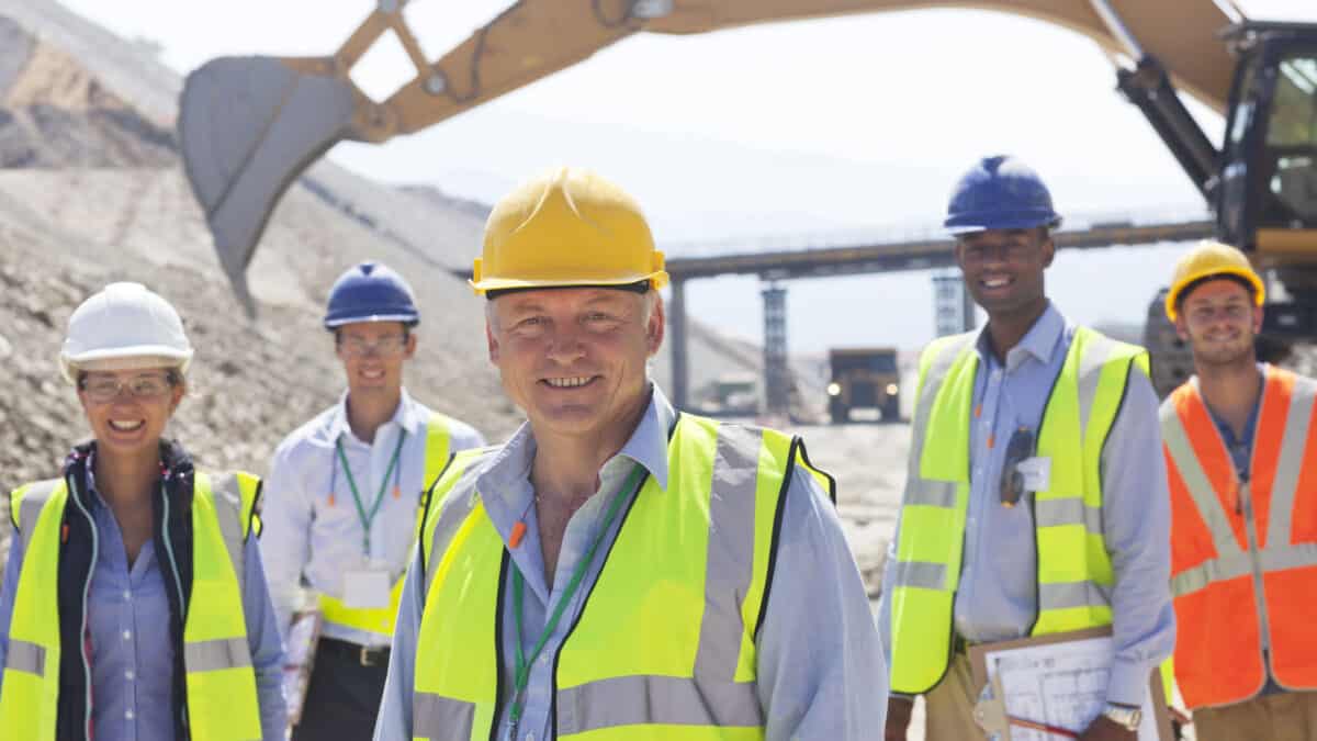 Business people standing at a mine site smiling.