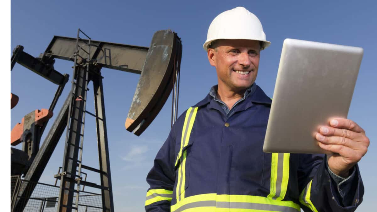 An oil worker in front of a pumpjack using a tablet PC.