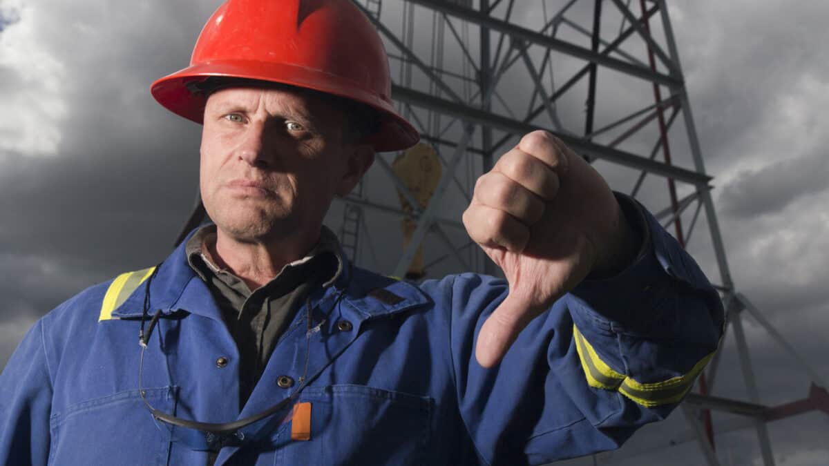 A negative oil worker giving the thumbs down on the falling price of oil.