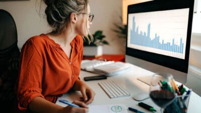 Business women working from home with stock market chart showing per cent change on her laptop screen.