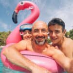 Family of father and children taking selfie while playing in a pool on holidays.