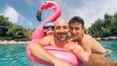 Family of father and children taking selfie while playing in a pool on holidays.