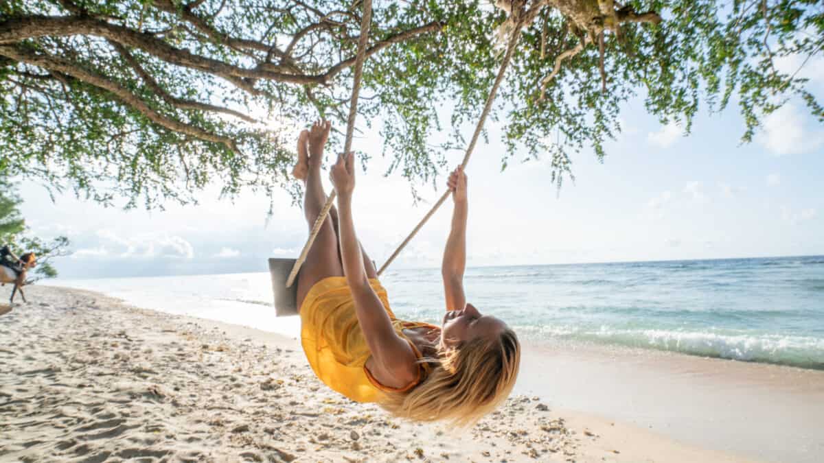 Woman on a swing at a beach, symbolising passive income.