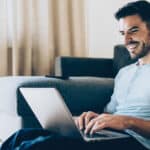 Man smiling at a laptop because of a rising share price.