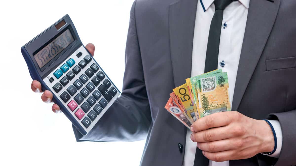 Man holding a calculator with Australian dollar notes, symbolising dividends.