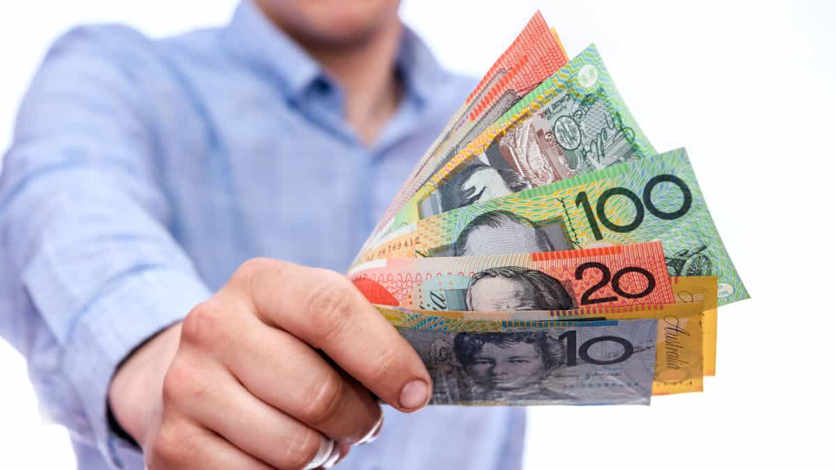 Man holding out Australian dollar notes, symbolising dividends.