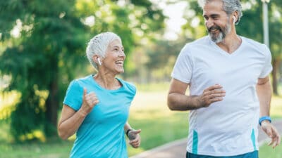 Two people smiling at each other while running.