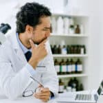 Scientist looking at a laptop thinking about the share price performance.