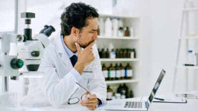 Scientist looking at a laptop thinking about the share price performance.