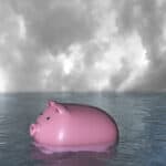 Piggy bank sinking in water symbolising a record low share price.