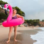 Woman with a floatable flamingo at a beach, symbolising passive income.