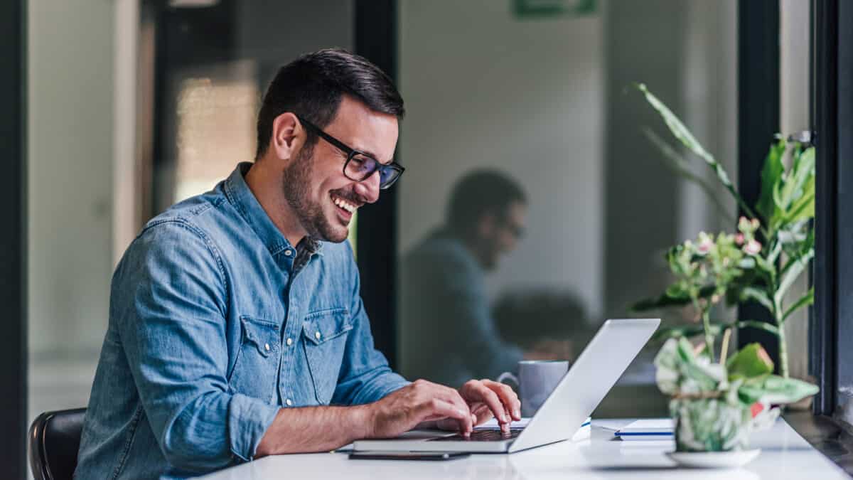 Delighted adult man, working on a company slogan, on his laptop.