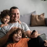 Happy dad watching tv with kids, symbolising passive income.