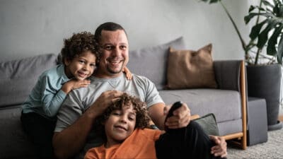 Happy dad watching tv with kids, symbolising passive income.