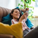 Woman relaxing on her phone on her couch, symbolising passive income.