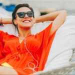 A woman in hammock with headphones on enjoying life which symbolises passive income.