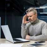 A concerned man looking at his laptop.