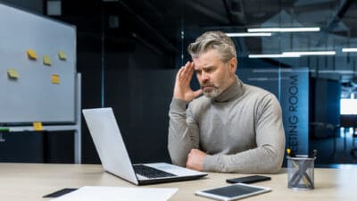 A concerned man looking at his laptop.