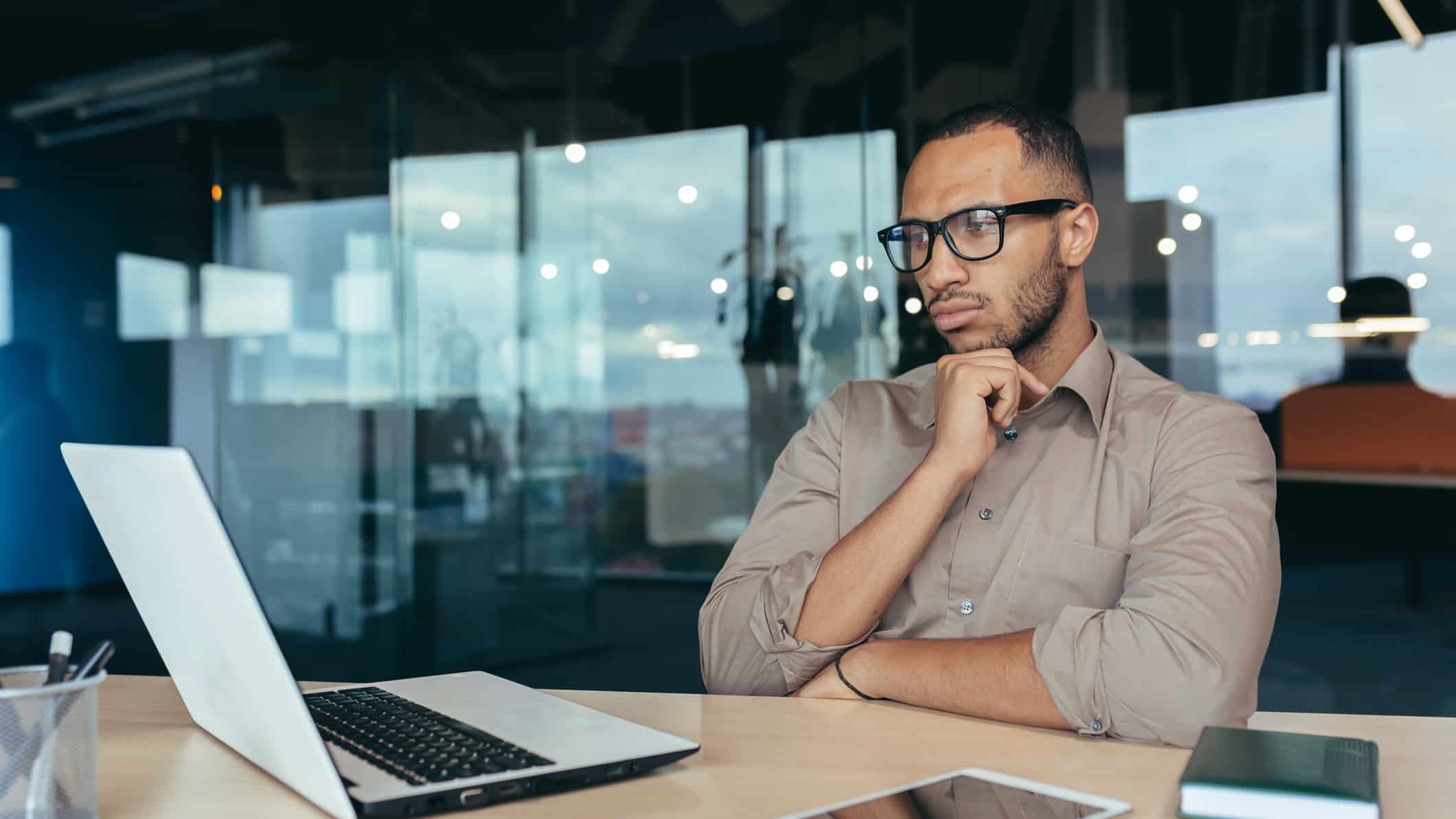 A man looking at his laptop and thinking.