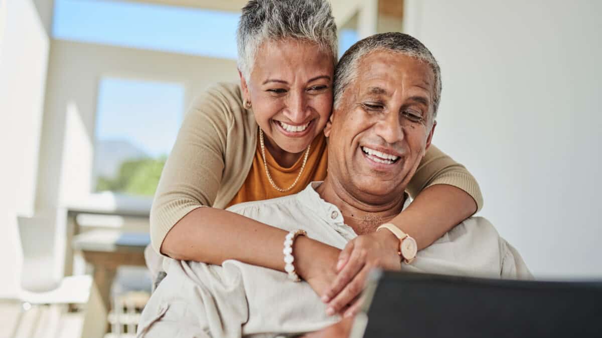 Smiling elderly couple looking at their superannuation account, symbolising retirement.