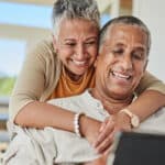 Smiling elderly couple looking at their superannuation account, symbolising retirement.
