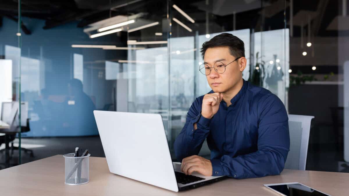 A man looking at his laptop and thinking.