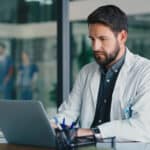 Health professional looking at a laptop.