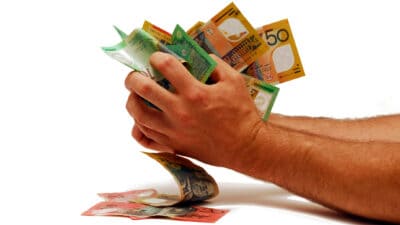 Person with a handful of Australian dollar notes, symbolising dividends.
