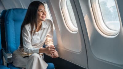 Smiling woman looking through a plane window.