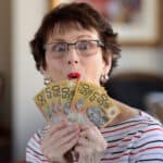 Woman holding $50 notes with a delighted face.