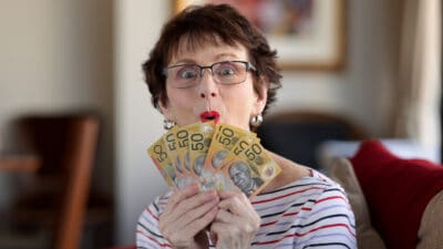 Woman holding $50 notes with a delighted face.
