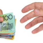 Hand with Australian dollar notes handing the money to another hand symbolising ex-dividend date.