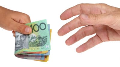 Hand with Australian dollar notes handing the money to another hand symbolising ex-dividend date.