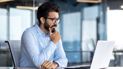 A man looking at his laptop and thinking.