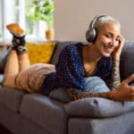 Woman with headphones on relaxing and looking at her phone happily.