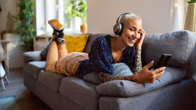 Woman with headphones on relaxing and looking at her phone happily.