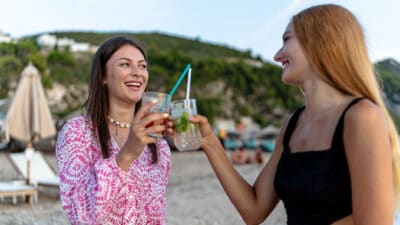 The sea's vastness is rivalled only by the refreshing feel of the drinks two friends share as they saunter along its edge, symbolising passive income.