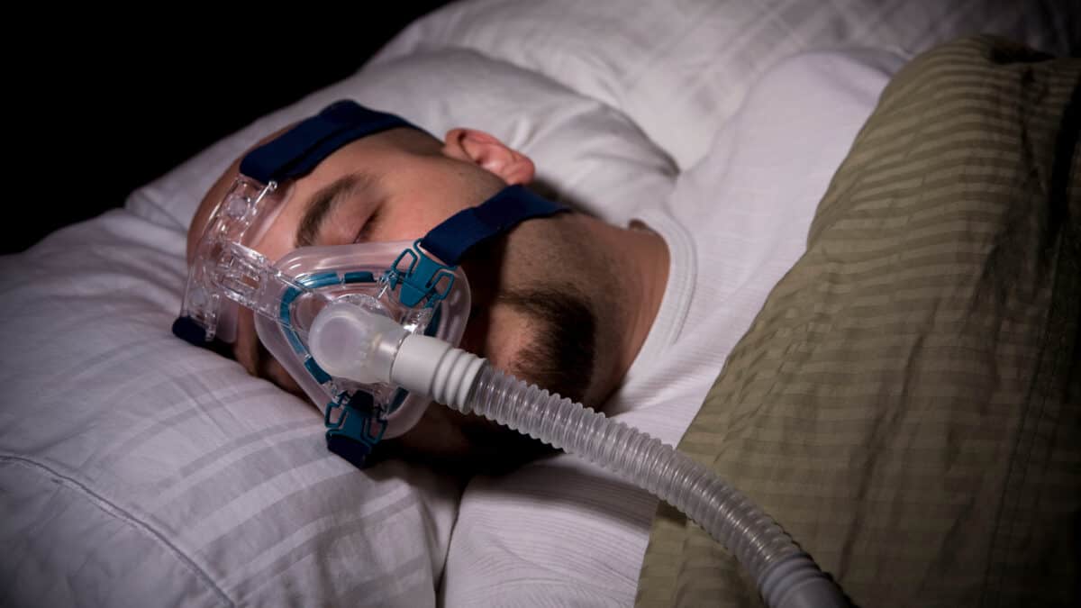 Man sleeping with a sleep apnoea mask on.