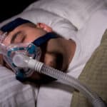 Man sleeping with a sleep apnoea mask on.