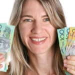 Smiling woman holding Australian dollar notes in each hand, symbolising dividends.