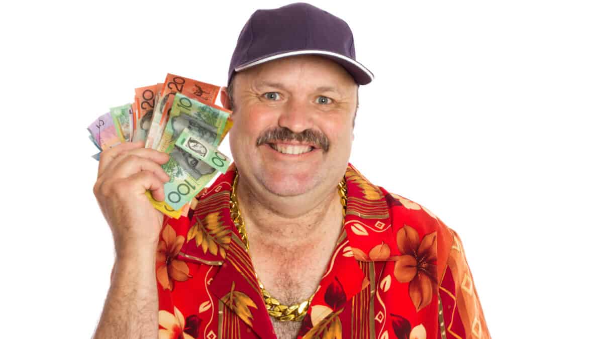 Happy man in a holiday shirt holding out Australian dollar notes, symbolising dividends.