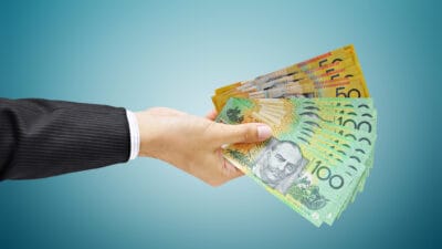 Hand holding Australian dollar (AUD) bills, symbolising ex dividend day. Passive income.