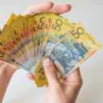 Man holding fifty Australian Dollar banknote in his hands, symbolising dividends, symbolising dividends.