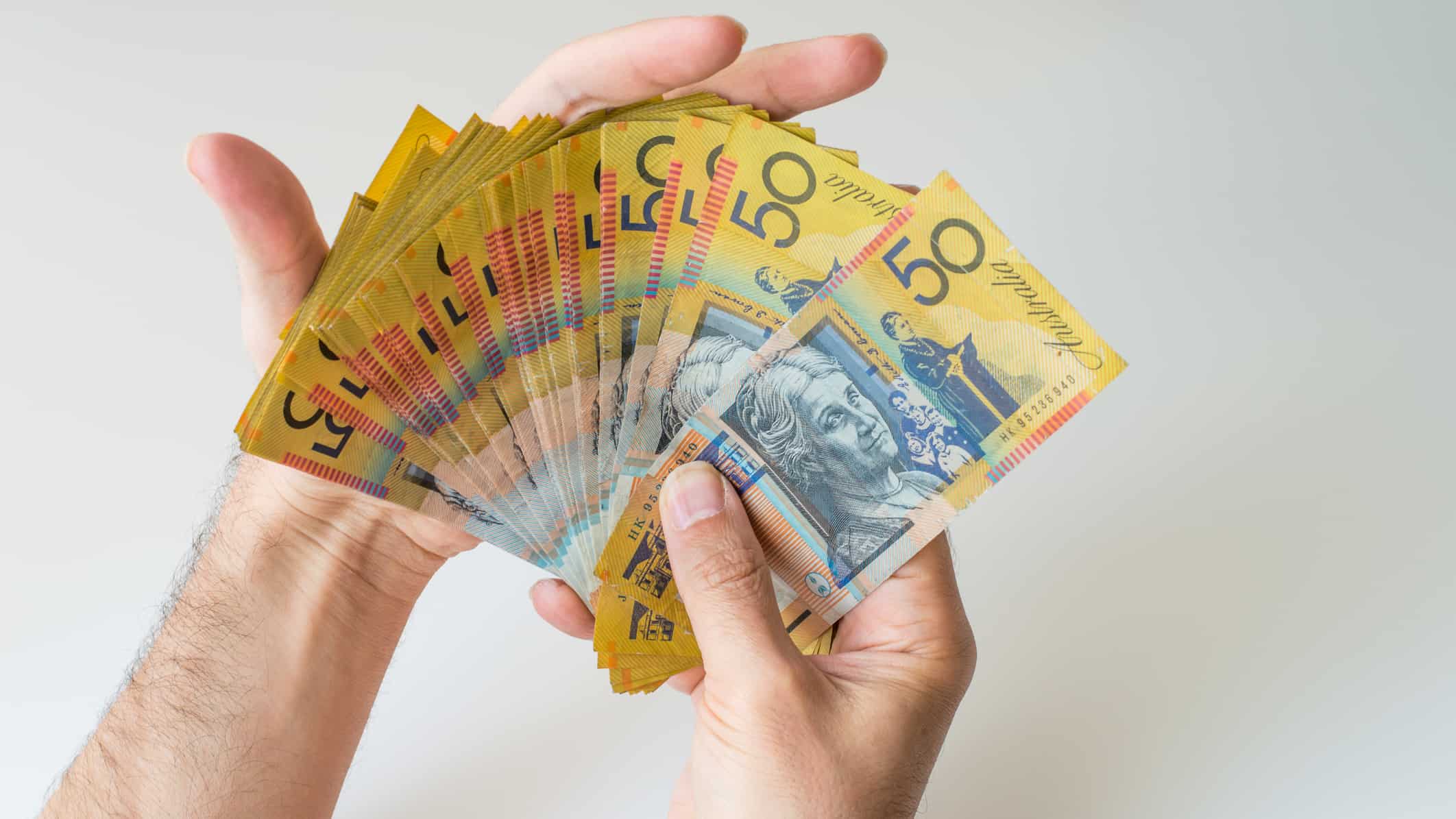 Man holding fifty Australian Dollar banknote in his hands, symbolising dividends, symbolising dividends.