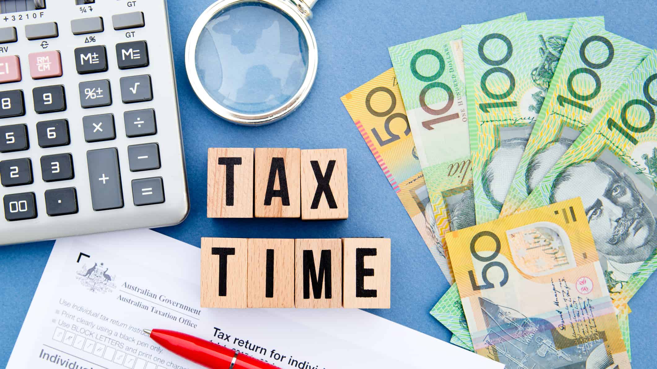 Tax time written on wooden blocks next to a calculator and Australian dollar notes.