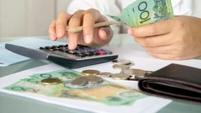 Accountant woman counting an Australian money and using calculator for calculating dividend yield.