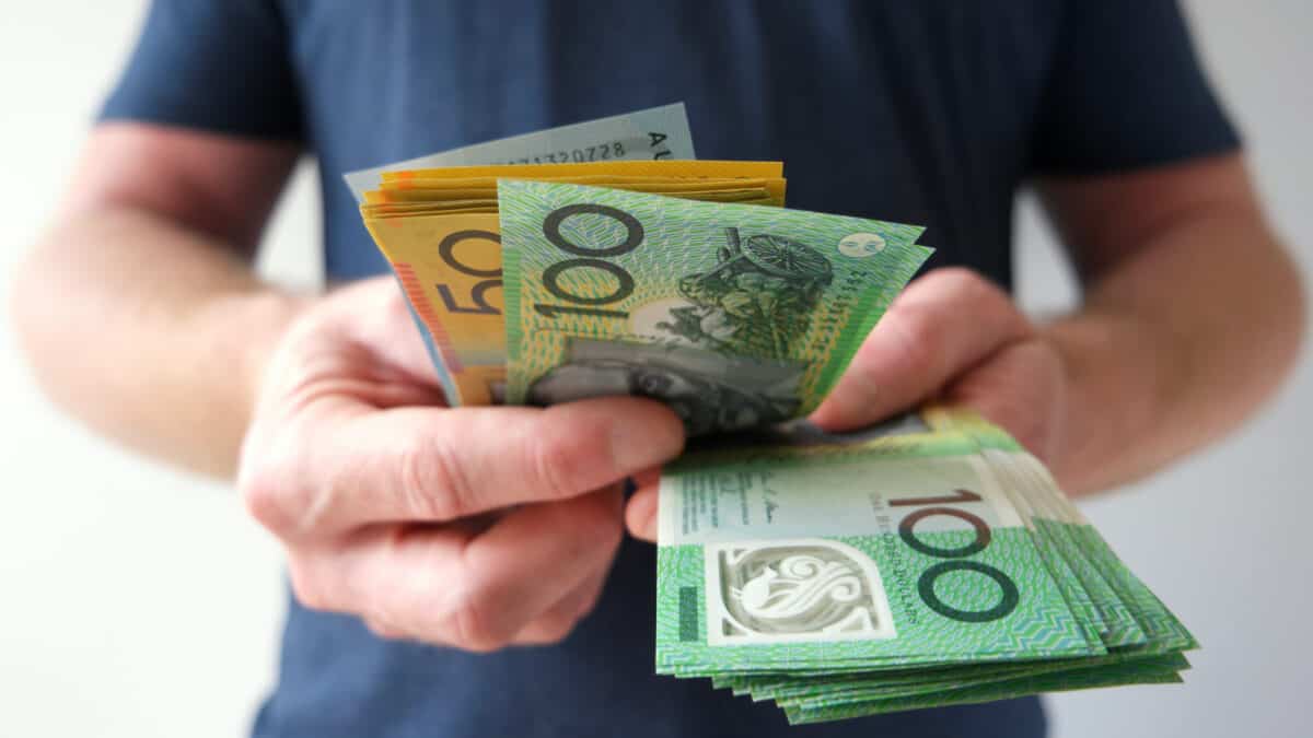 Man holding out Australian dollar notes, symbolising dividends.