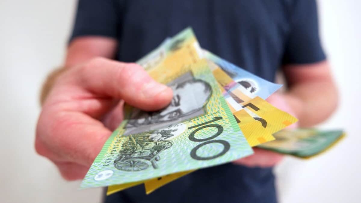 Person handing out $100 notes, symbolising ex-dividend date.