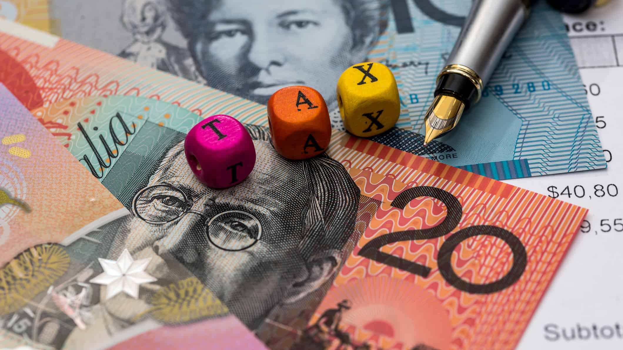 Cubes with tax written on them on top of Australian dollar notes.